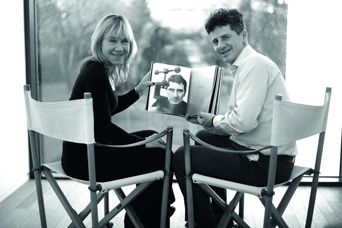 Two people holding a photo while sitting on director's chairs.