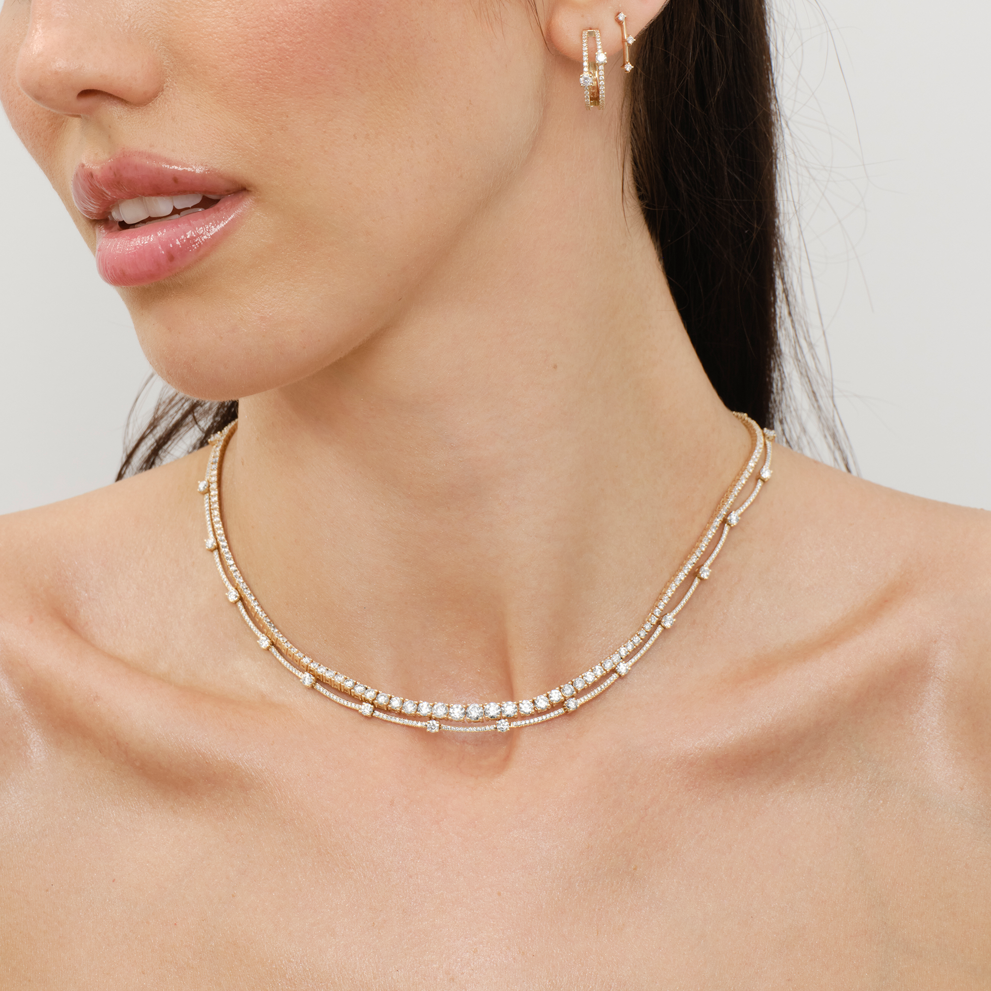 Woman wearing a stylish necklace and earrings, showcasing her neck and shoulders.