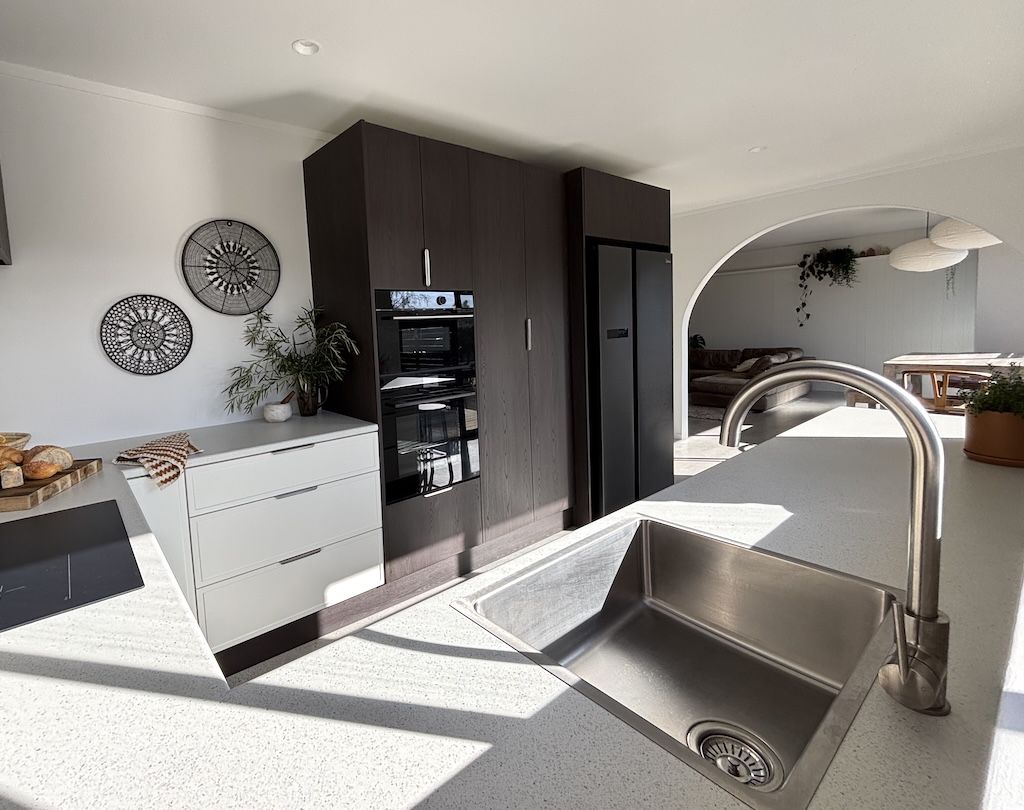 Modern kitchen with stainless steel sink, dark cabinets, and decorative wall plates.