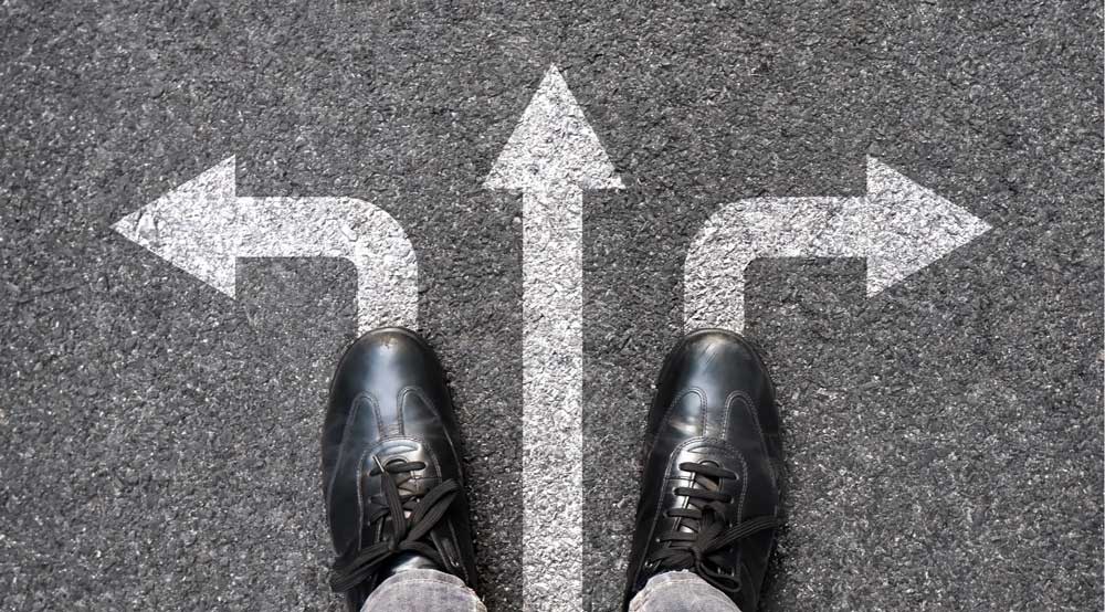 Overhead view of feet standing at a three-way junction.