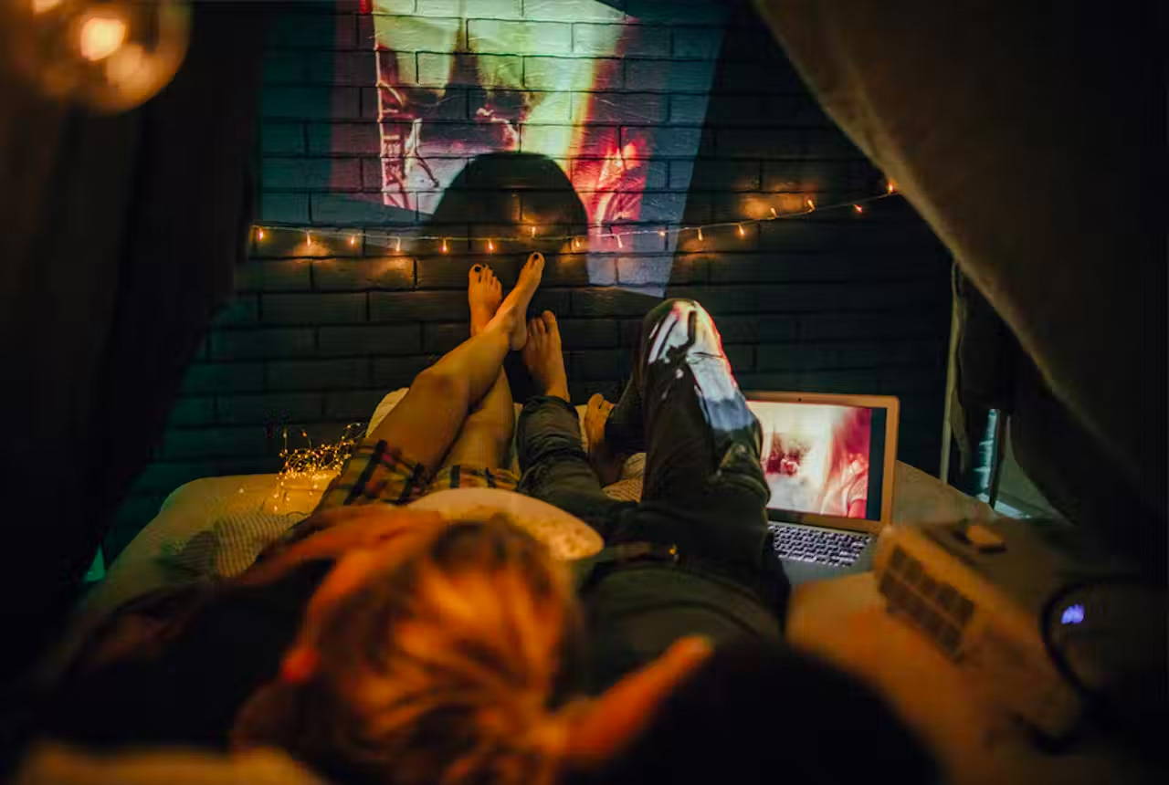 Couple watching a movie that is projected on an outside brick wall of their home.