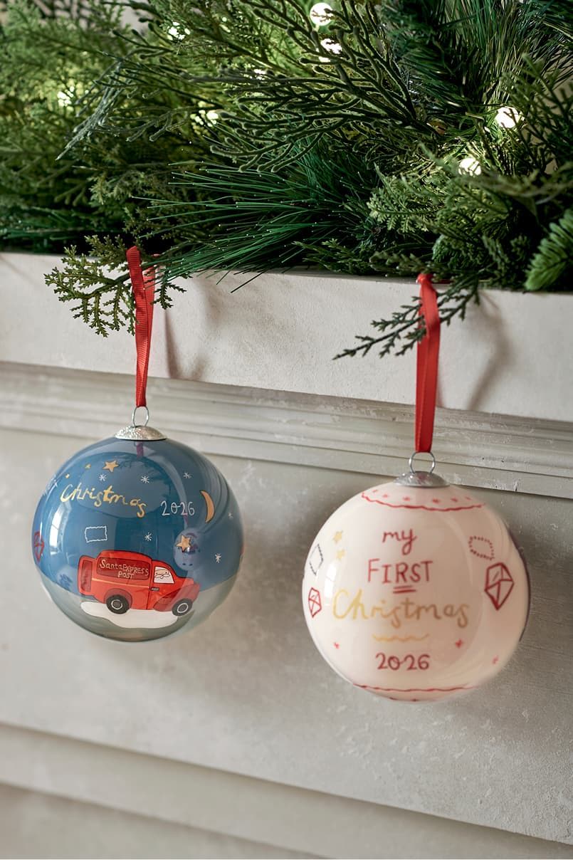Two Christmas ornaments hanging from a garland. One says 