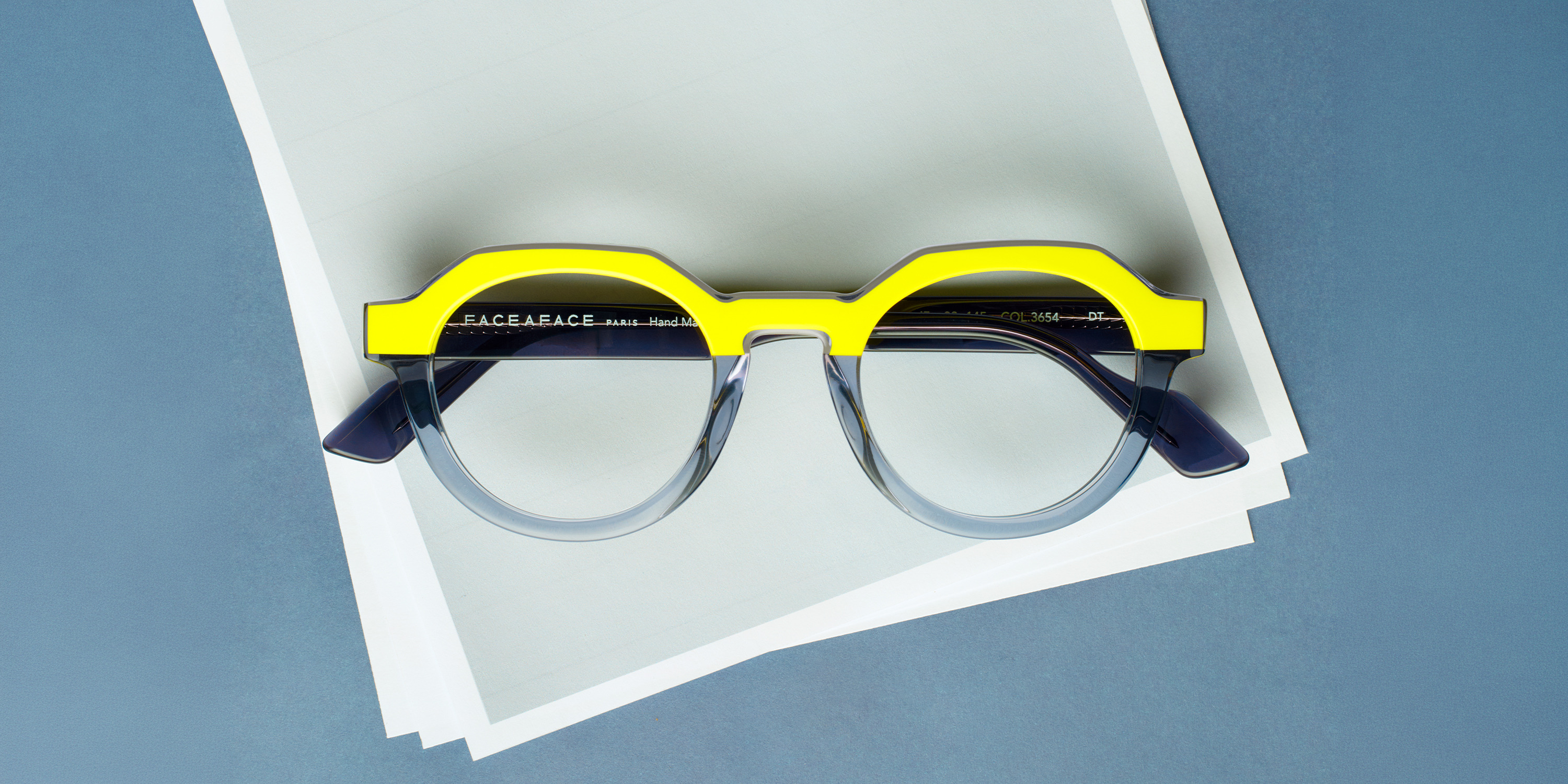 Colorful Face a Face glasses resting on a stack of white papers.