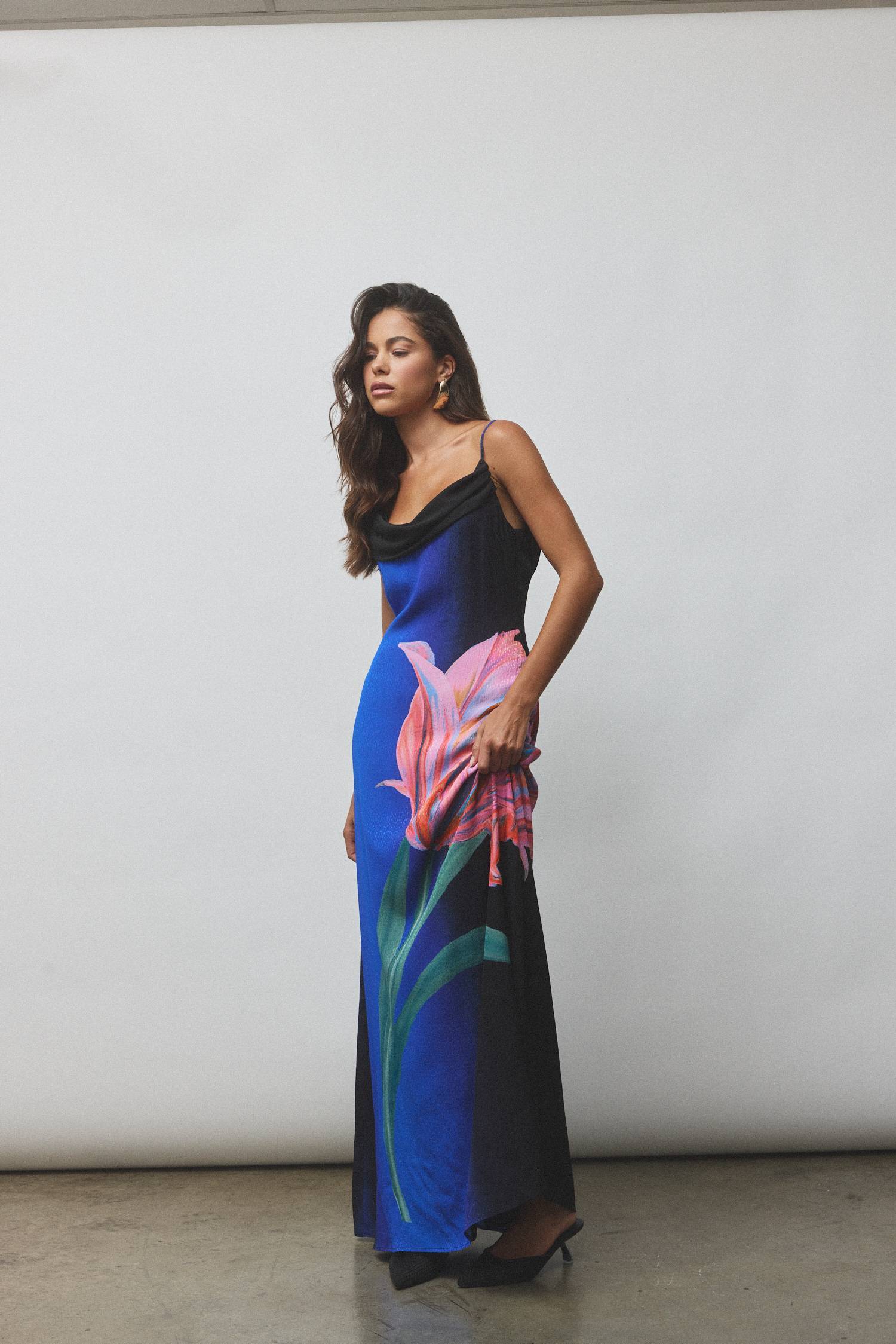 Model wearing a blue dress with pink flower design against a neutral background.