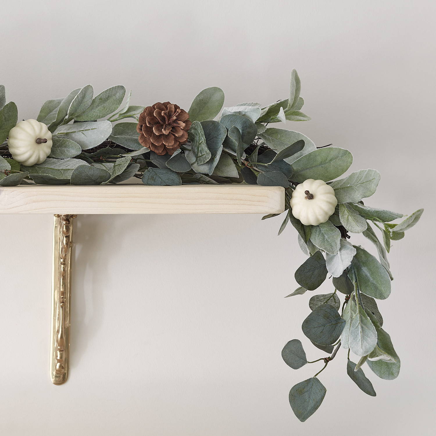 Neutral green eucalyptus garland featuring pine cones and white pumpkins