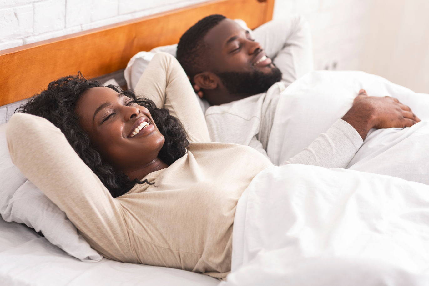 A couple sitting on a ergo-pedic sleepbed with smiles on their faces after sex
