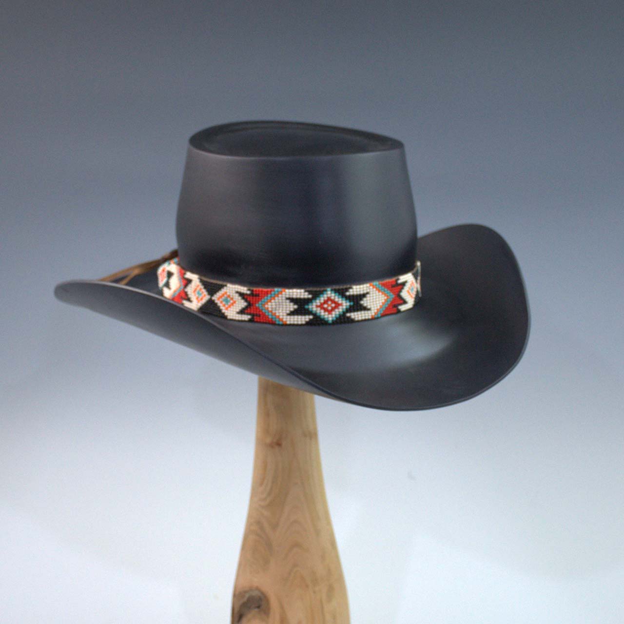 Black cowboy hat with a decorative band on a display stand.