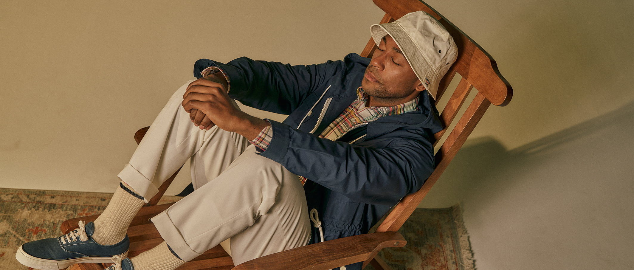 A person sitting in a rocking chair, wearing a hat and casual clothing.