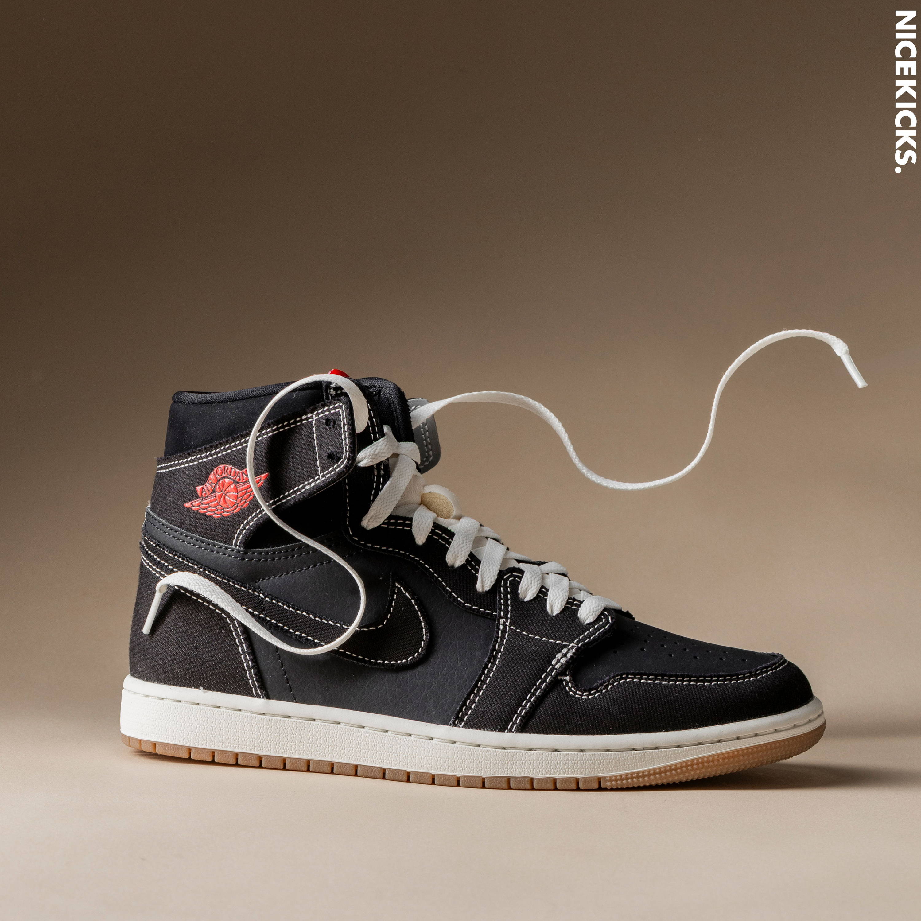 Black high-top sneaker with white laces on a neutral background.
