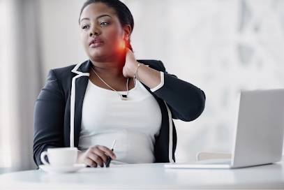 Woman at desk with laptop on table holding her neck in pain. 