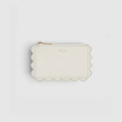 White scalloped wallet with a zipper on a gray background.
