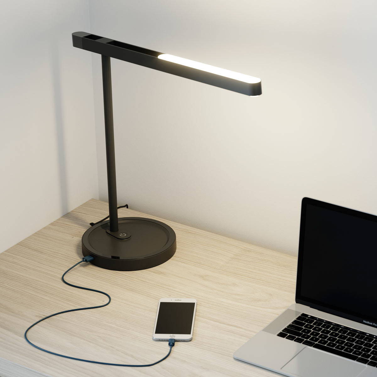 A LUX led desk lamp charges a smartphone on a computer desk.