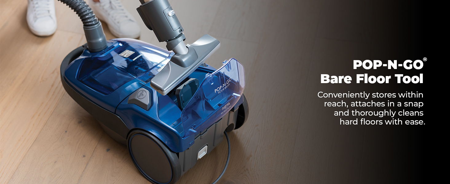 Vacuum cleaner with bare floor tool on wooden surface.