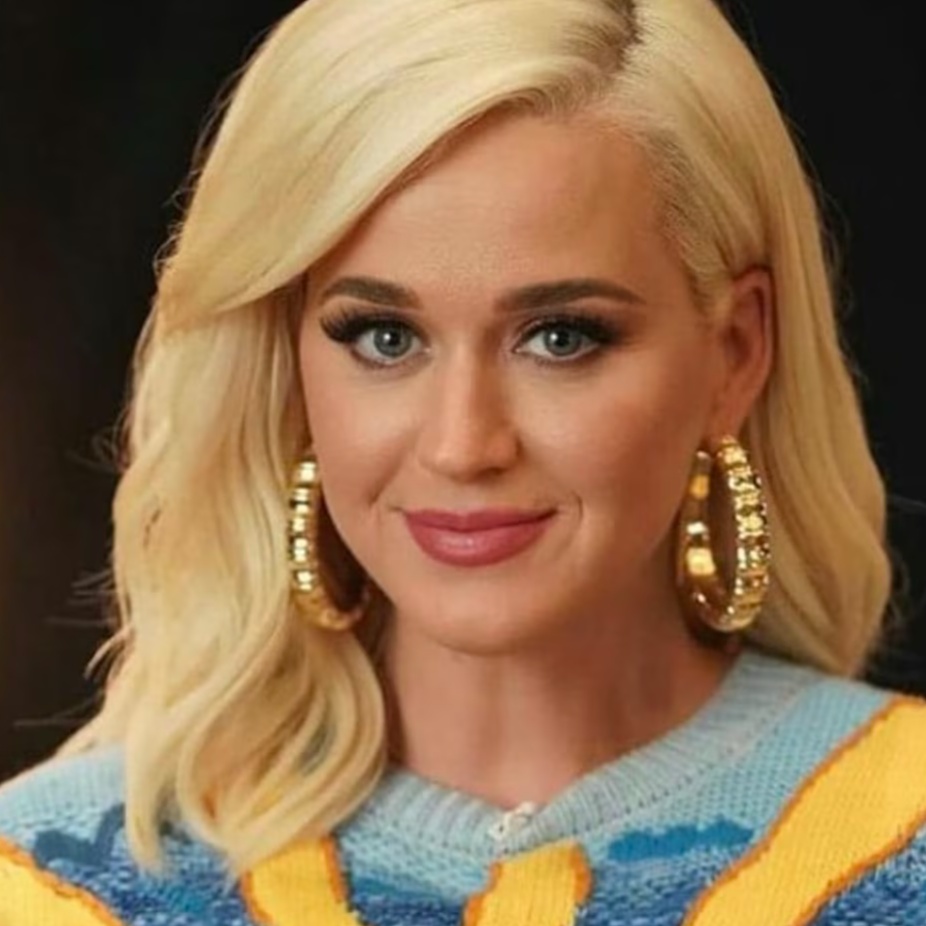 Woman with blonde hair, wearing large earrings and a colorful sweater.