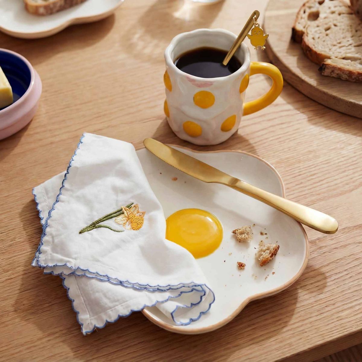 Breakfast scene with a mug, egg, napkin, and bread on a wooden table.