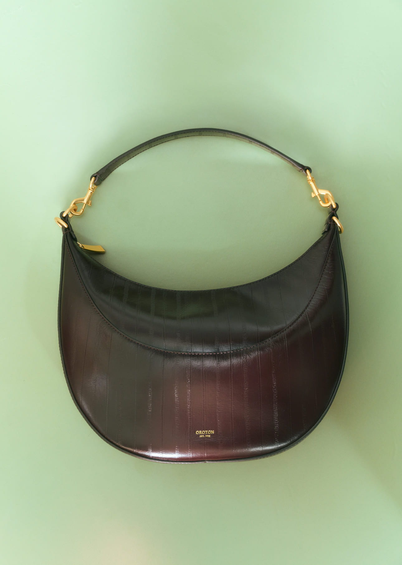 A stylish black handbag with a curved shape and gold accents.