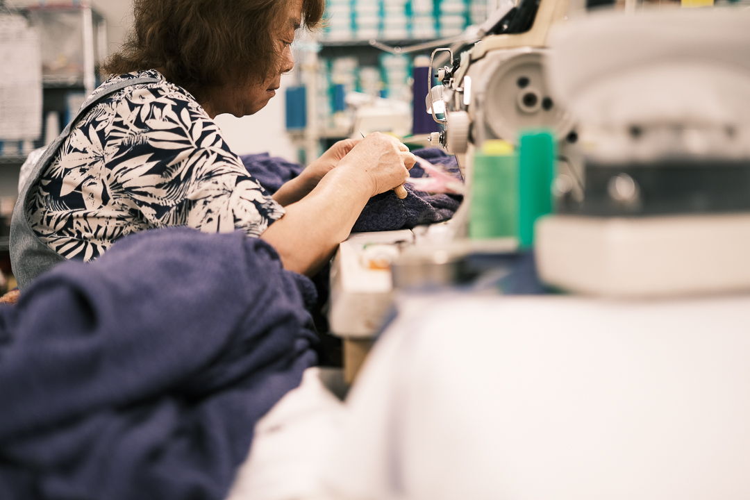 A woman sewing fabric at a sewing machine in a workshop.