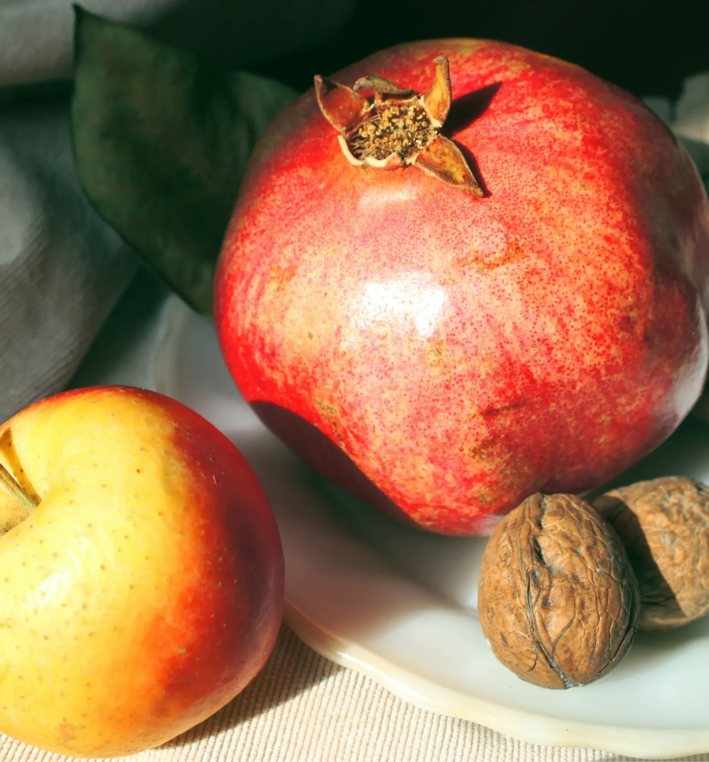 Pomegranate, apple, and chestnuts on a plate