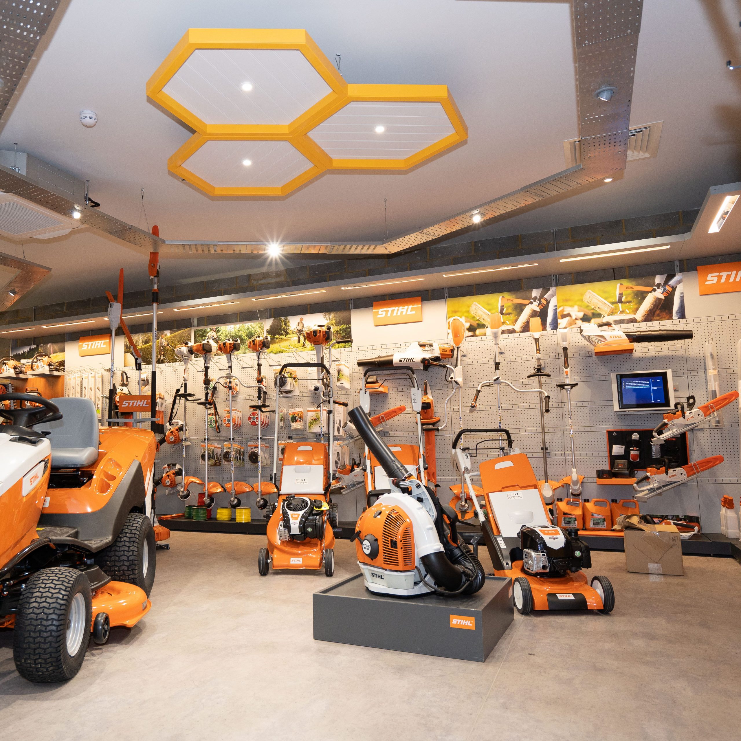 Showroom displaying various orange gardening and landscaping equipment and tools.