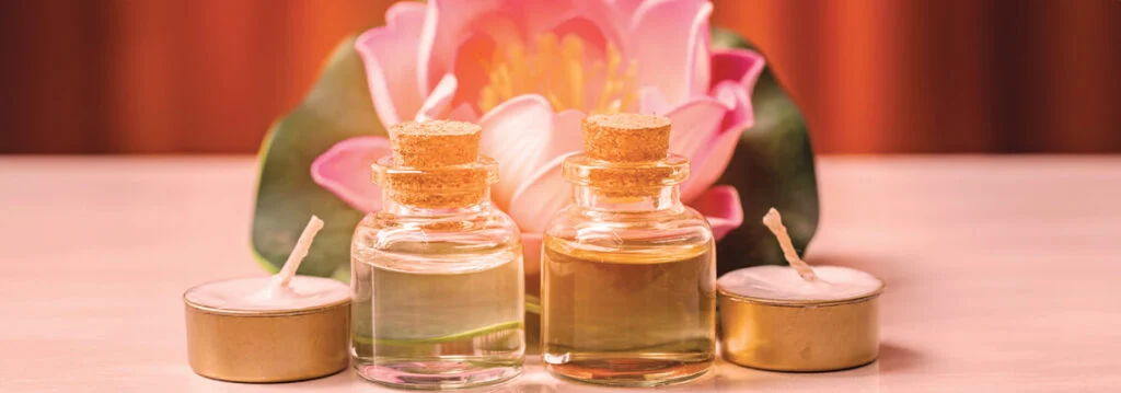 Bottles of essential oils with a pink flower in the background.