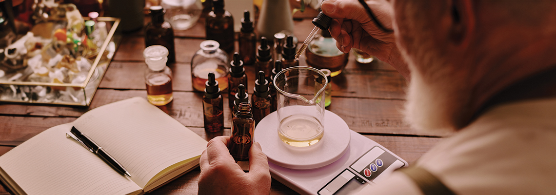A person holding a glass near various bottles and an open notebook.