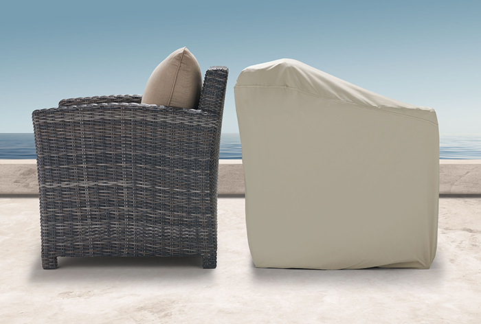 Two chairs, one woven and one covered, against a clear sky backdrop.