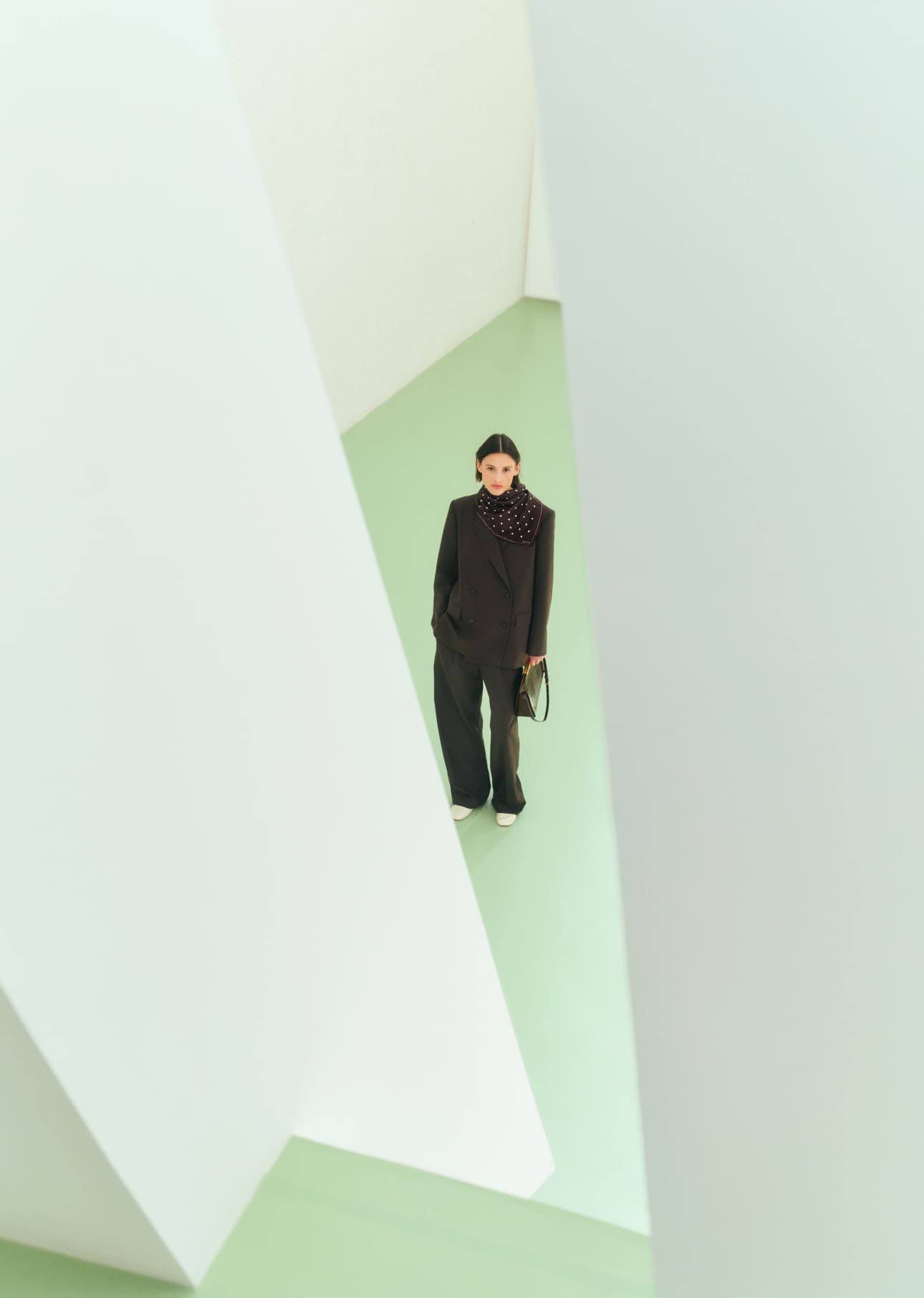 Person standing in a modern architectural space with green flooring and white walls.