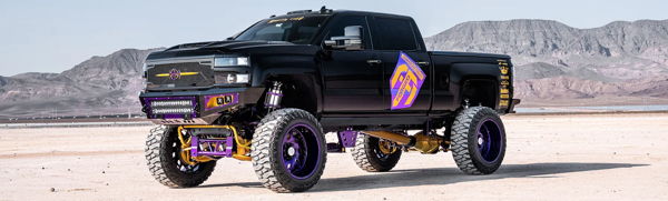 Front three-quarter view of Nicholas's black lifted 2016 Chevrolet Silverado 2500HD with purple and gold custom suspension in the desert, Nathan AirChime K5LA install photo 1