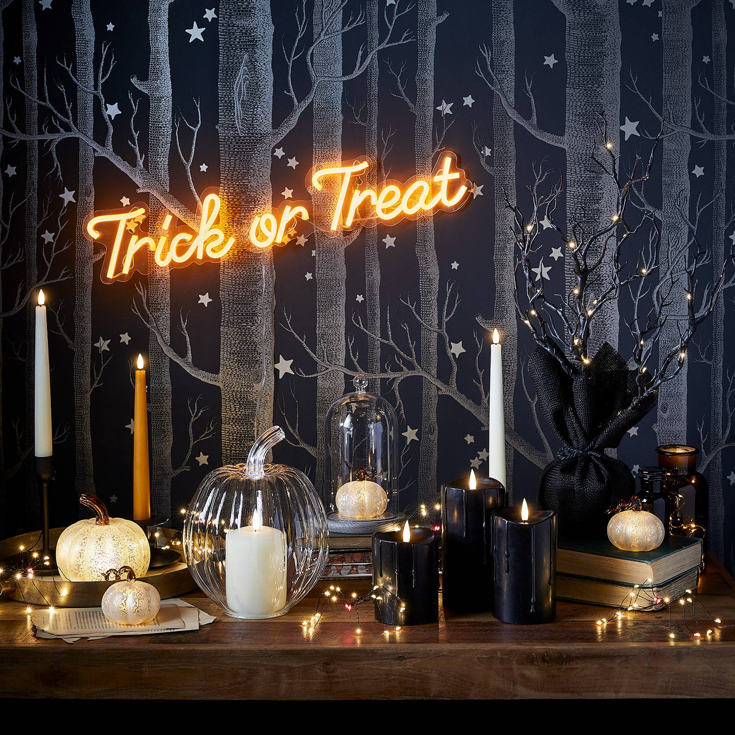 Halloween setting featuring neon lights,  LED taper and pillar candles and pumpkin decorations