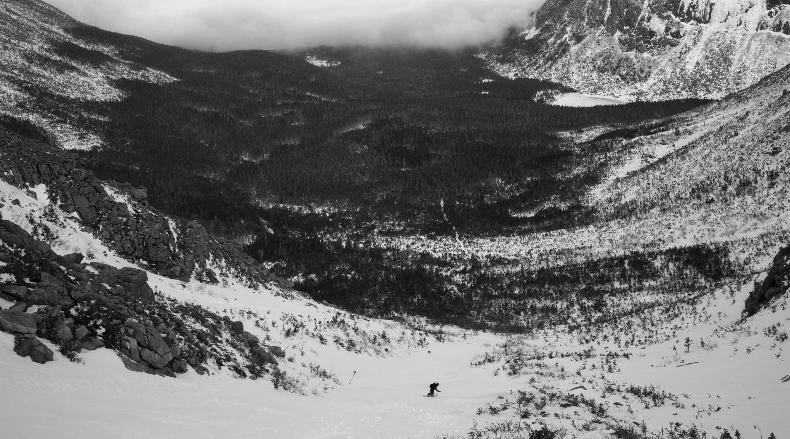 Black and white landscape of a snowy valley surrounded by mountains.