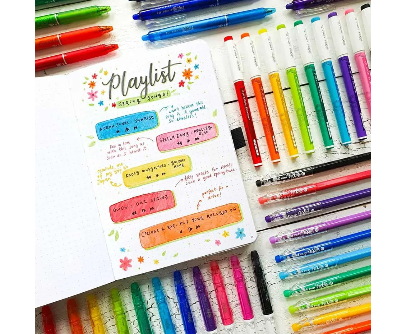A colourful bullet journal spread by AmandaRachLee showing a playlist of spring songs. Surrounded by neatly placed coloured pens.