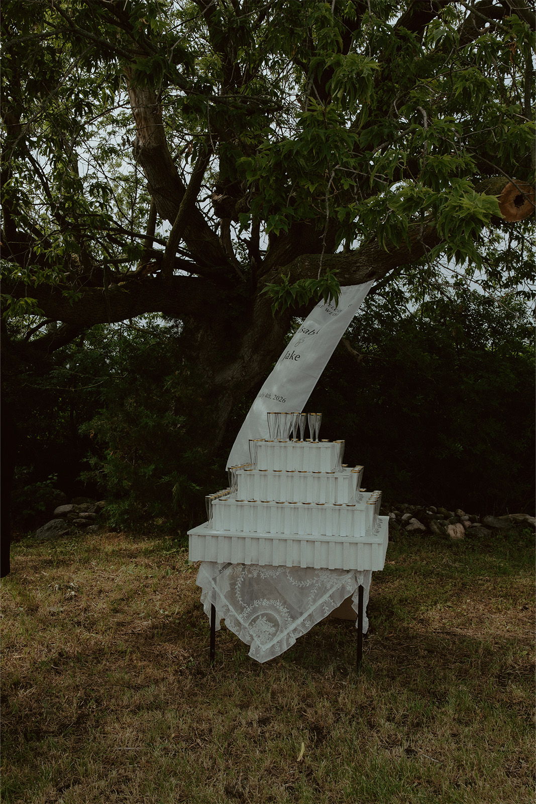 A white staircase installation under a tree in a grassy area.