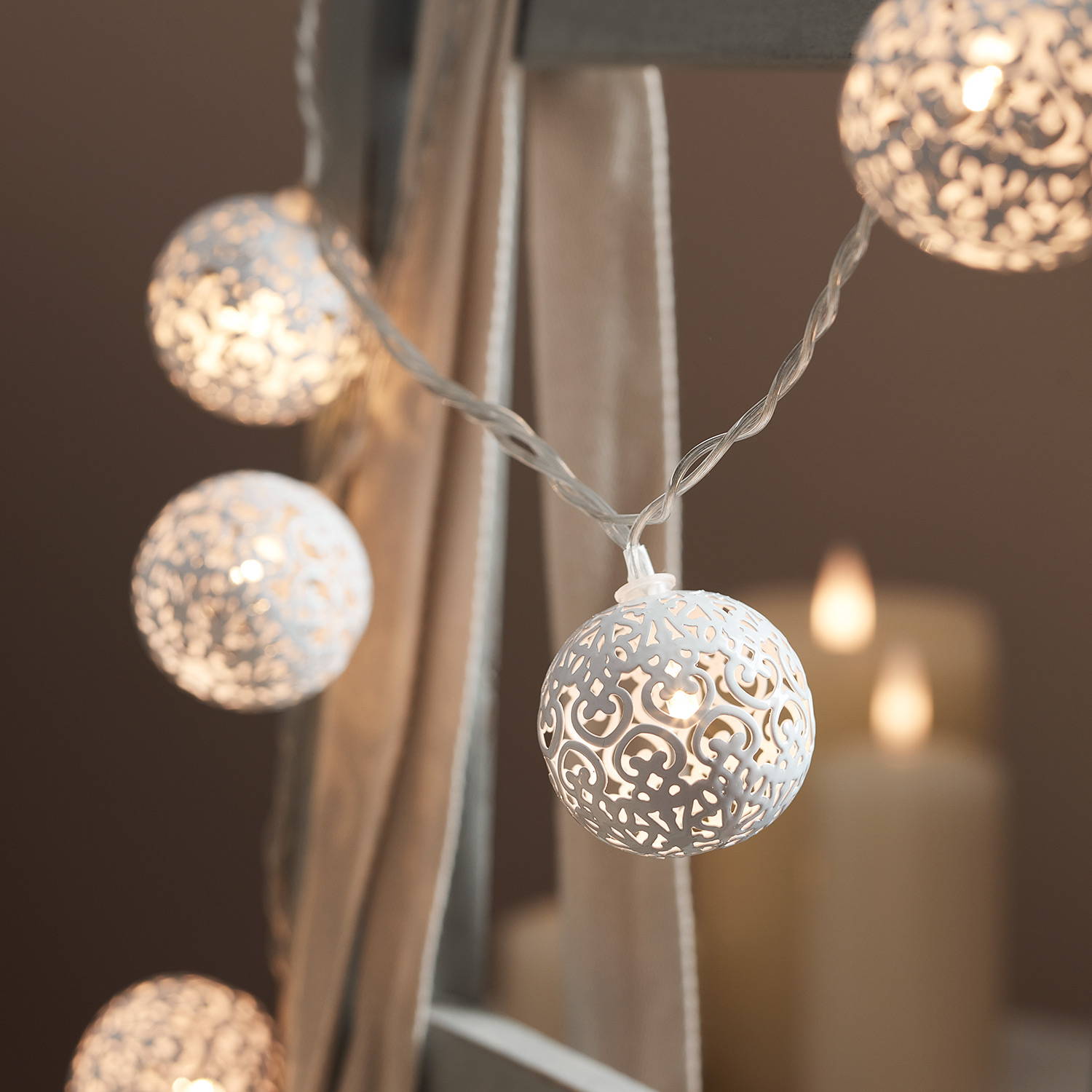A close up picture of white detailed fairy lights with LED candles in the background.