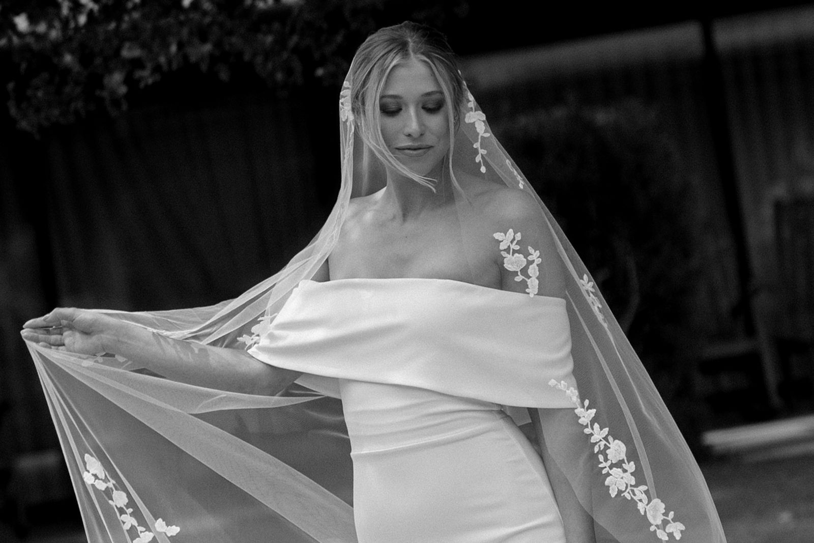 Bride in elegant wedding dress and veil, captured in black and white.