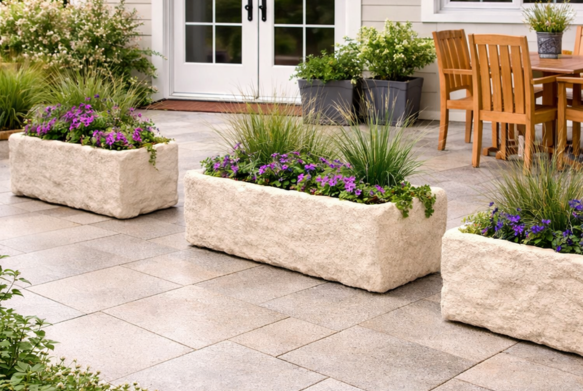 Three rectangular planters with flowers on a patio.
