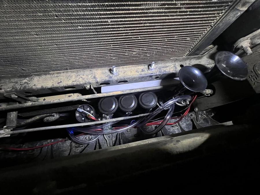 Four black horn trumpets mounted behind grille in front of radiator Trevor's 2005 Toyota 4 Runner Dixie musical horn gallery photo 5
