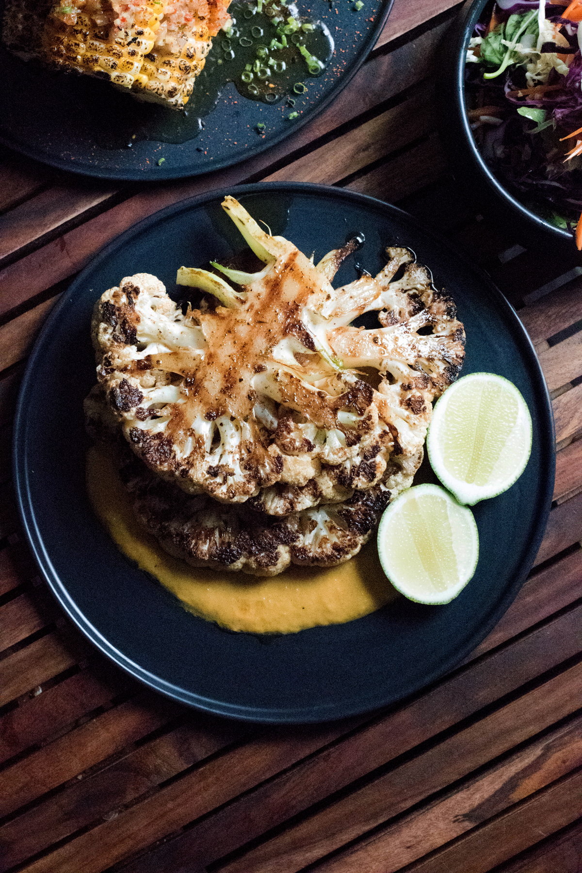 A plate with two grilled cauliflower florets on top of yellow sauce