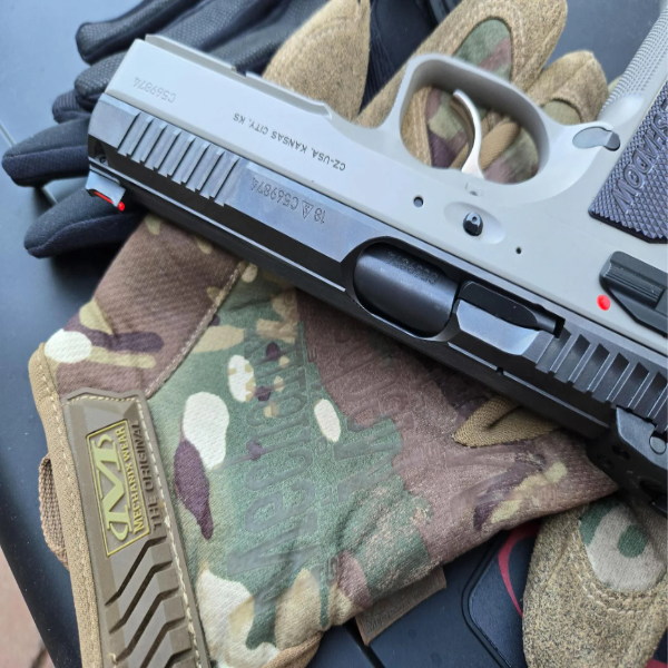 A handgun resting on camouflage gloves.