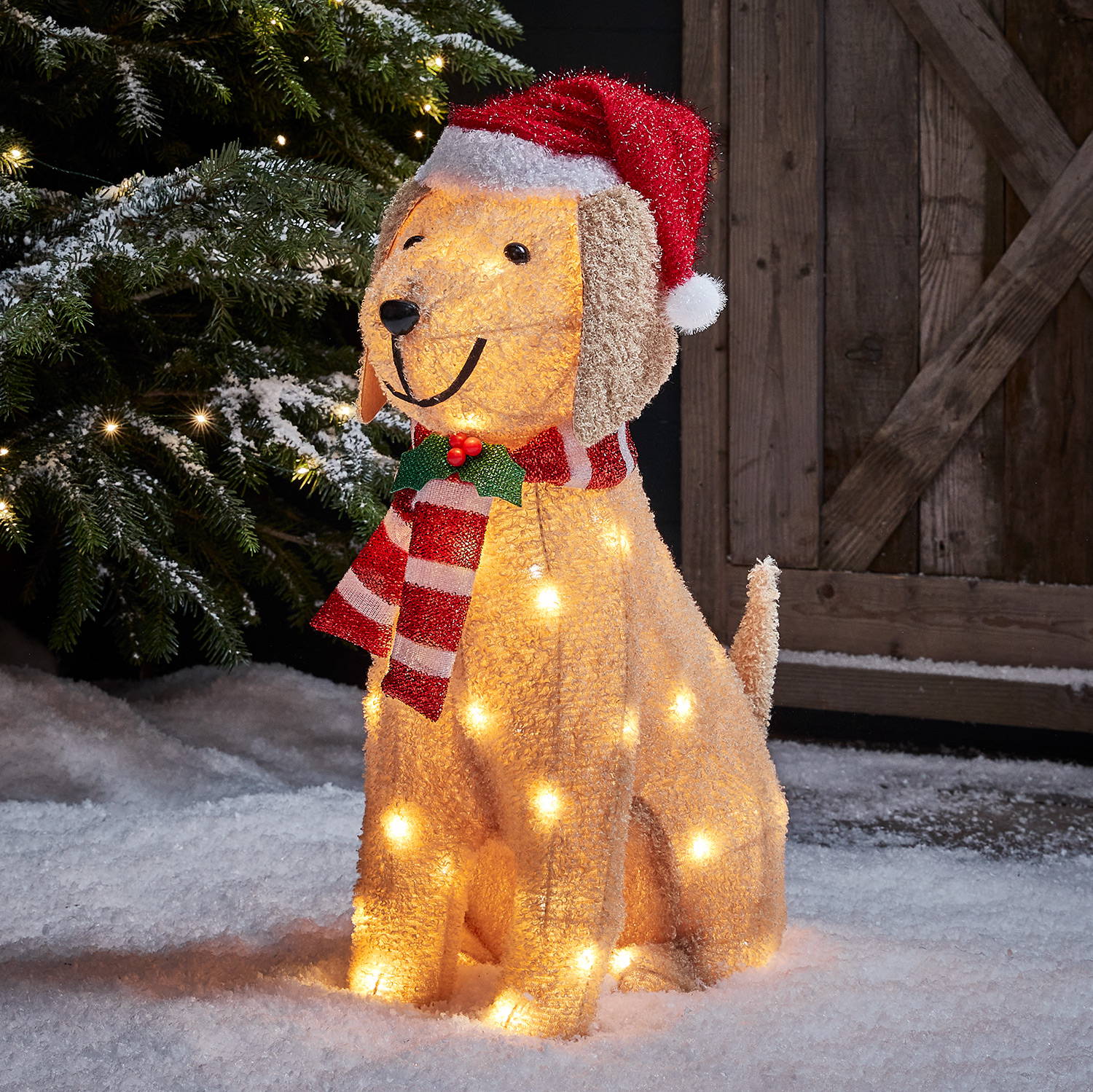 Fluffy Labrador figure sitting in a snowy garden with matching red hat and scarf  