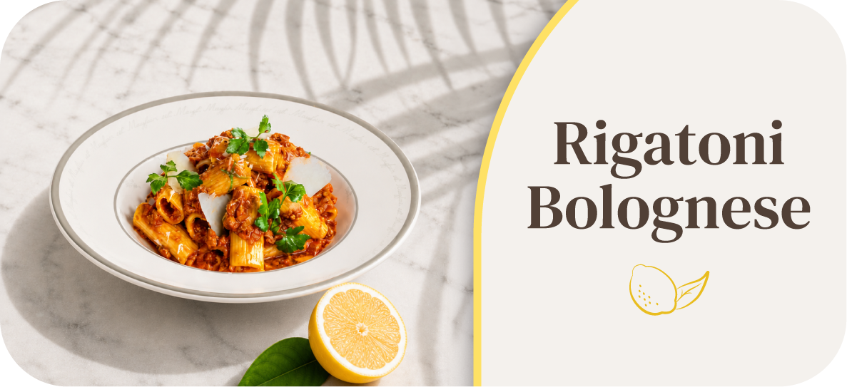 Plate of Rigatoni Bolognese with a lemon slice on the side.