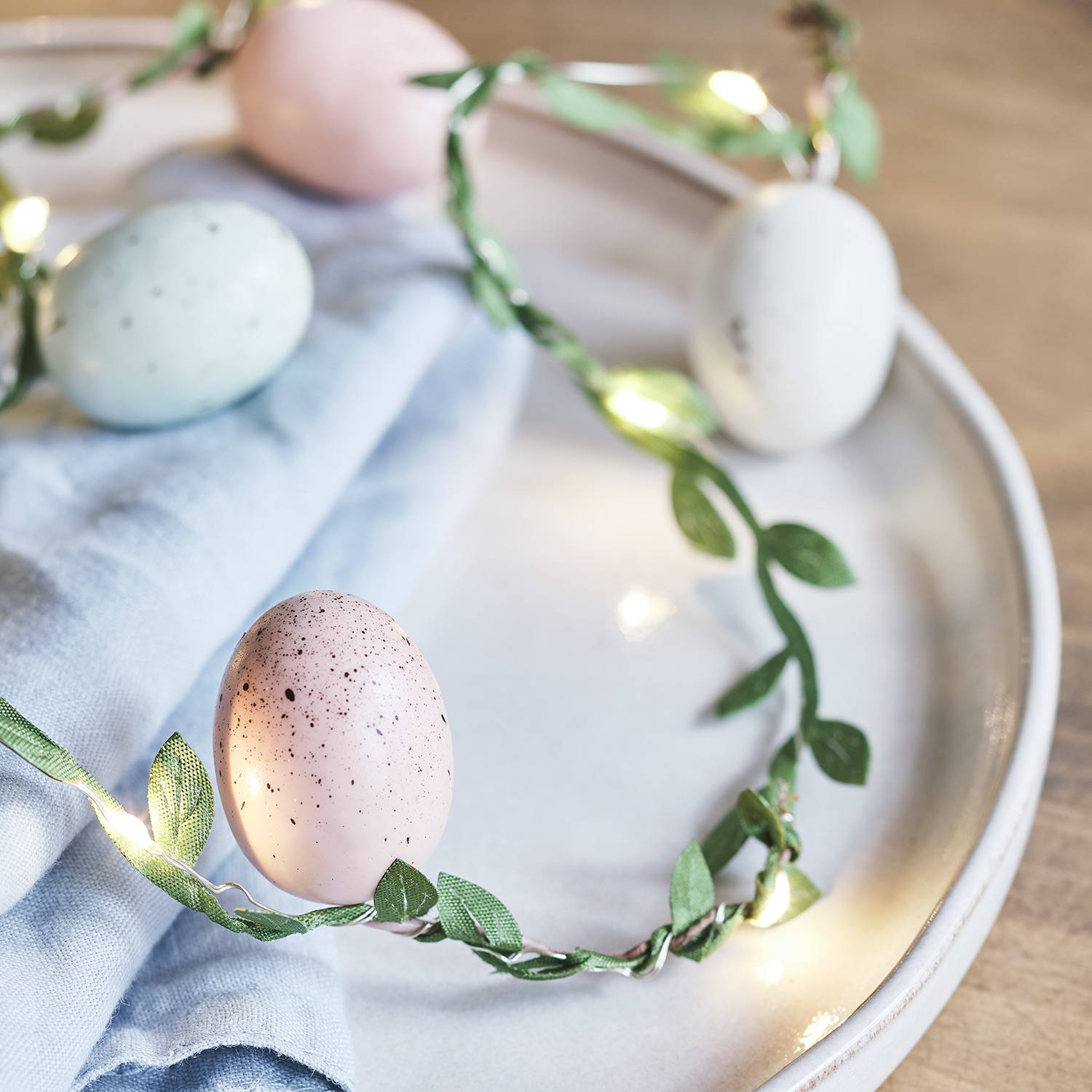 A close up of an Easter fairy light garland on a plate as part of an Easter dining table.