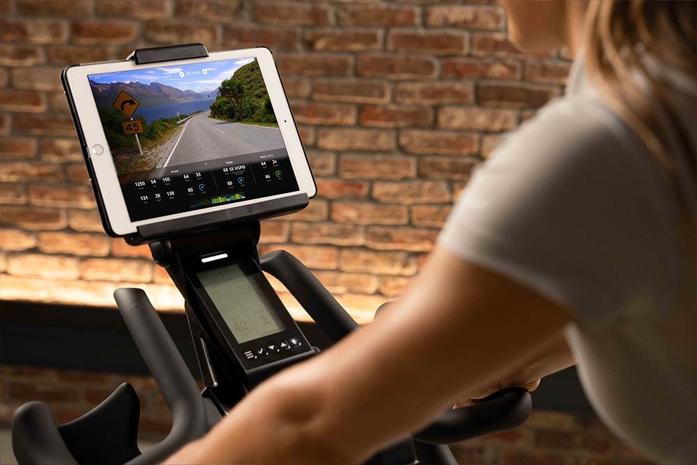 Female exercising on Ride CX with tablet on scenic ride