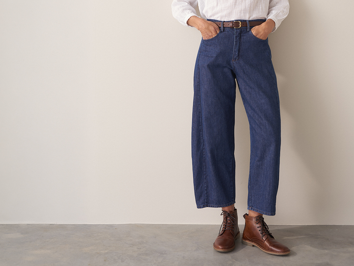 Woman wearing blue cotton denim trousers with brown lace up shoes and a white cotton top