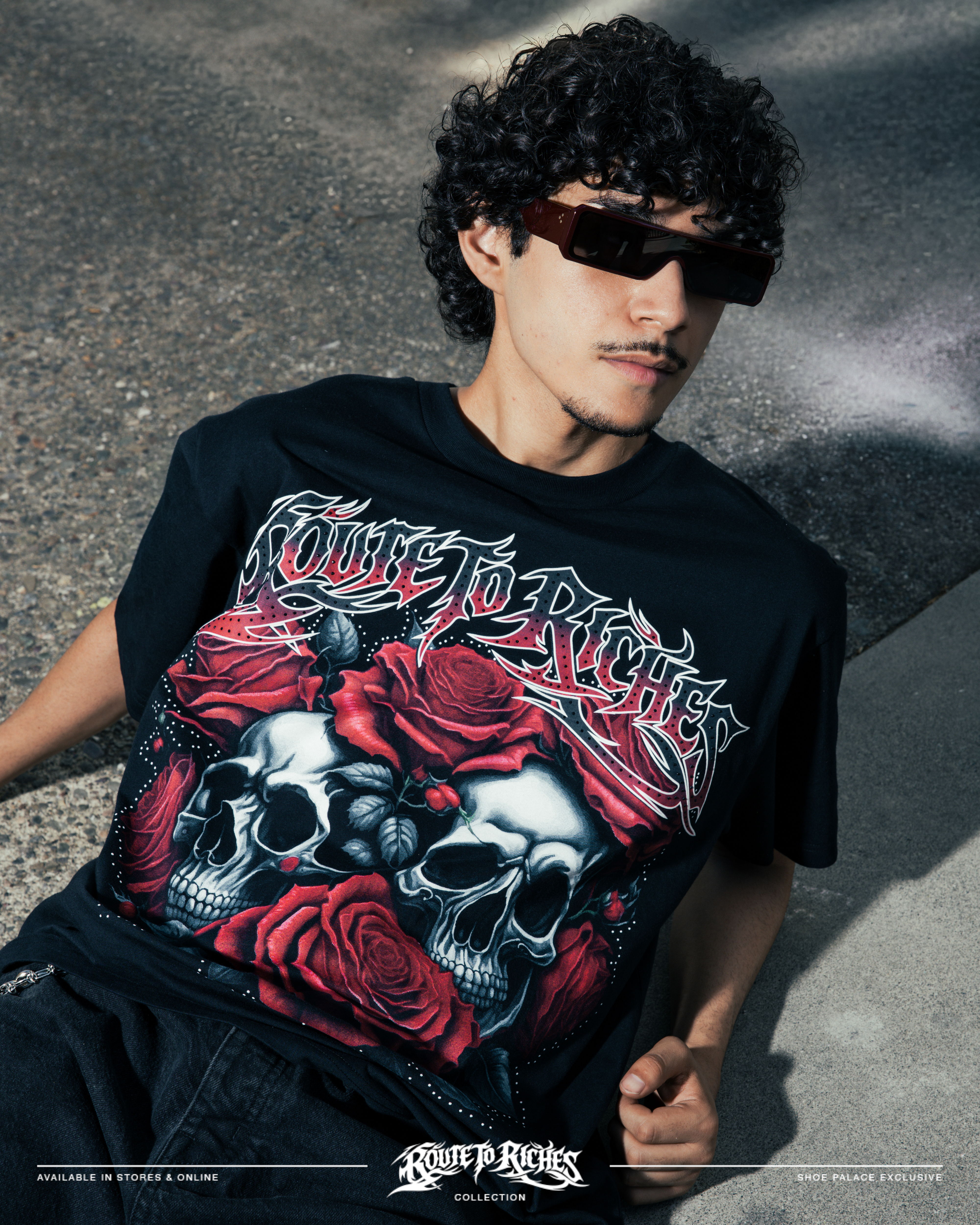 Person wearing sunglasses and a graphic t-shirt with skulls and roses.
