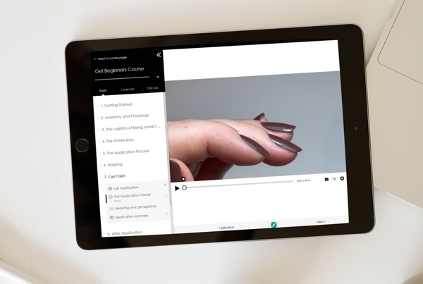 A hand with polished nails on a tablet screen.
