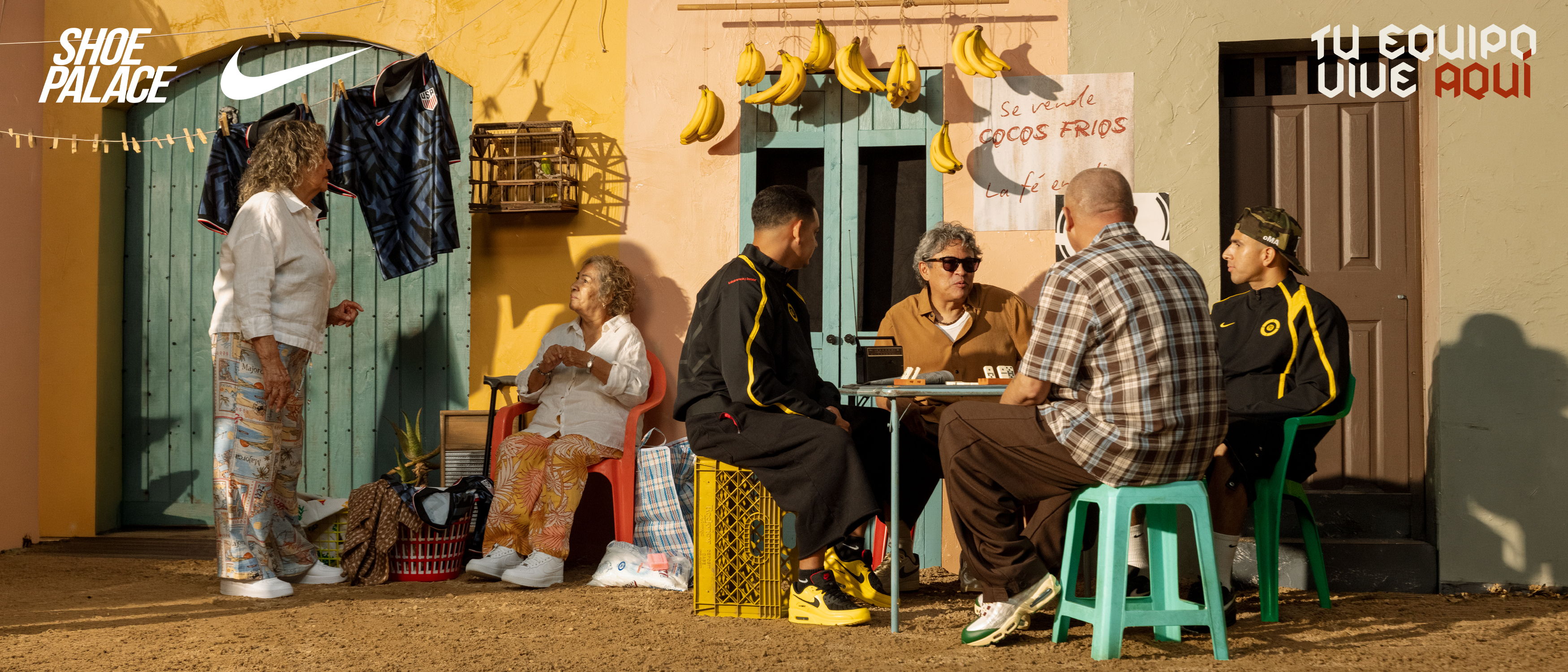 Group of people sitting around a table outside a colorful building.