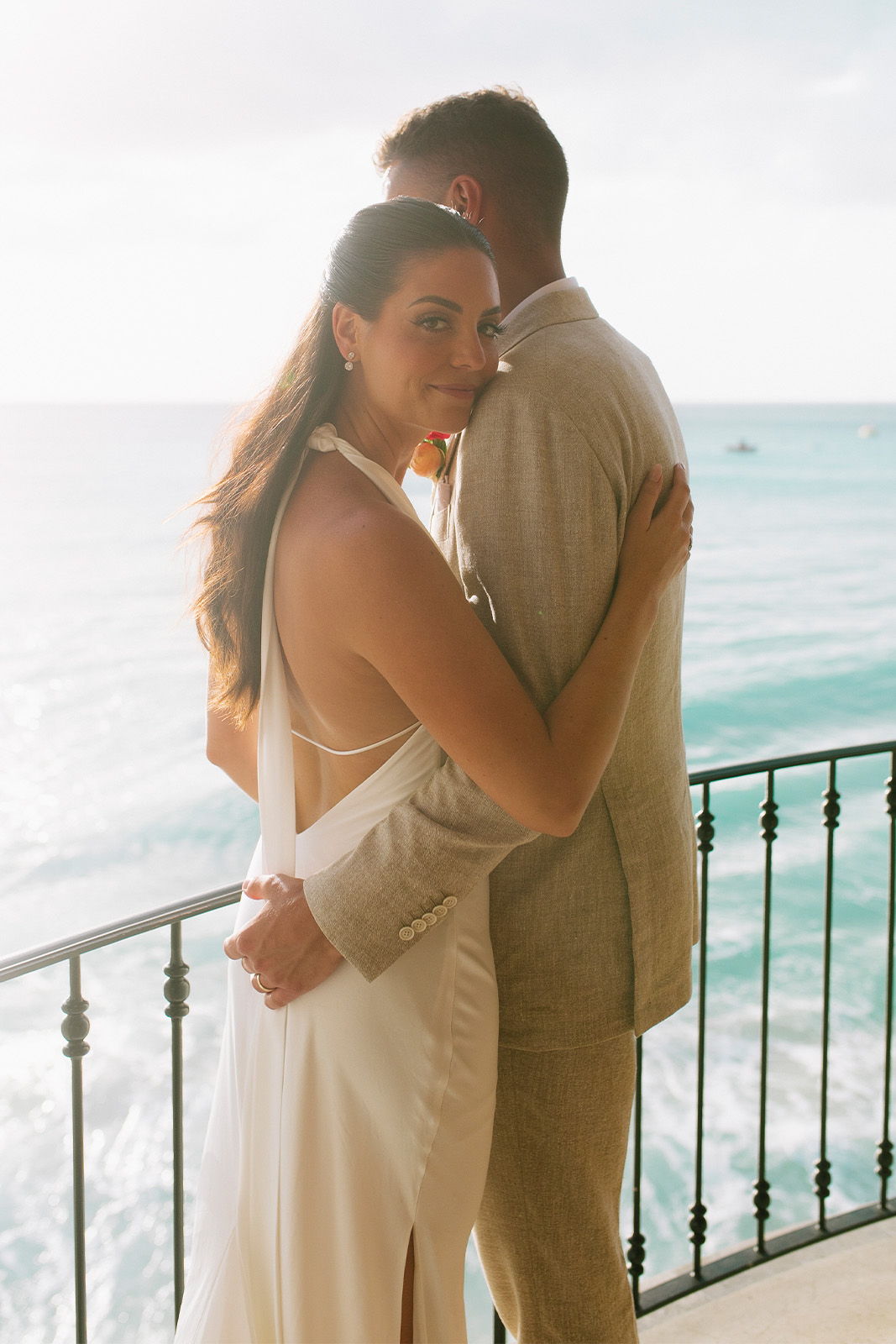 Couple embracing on a balcony with ocean view.