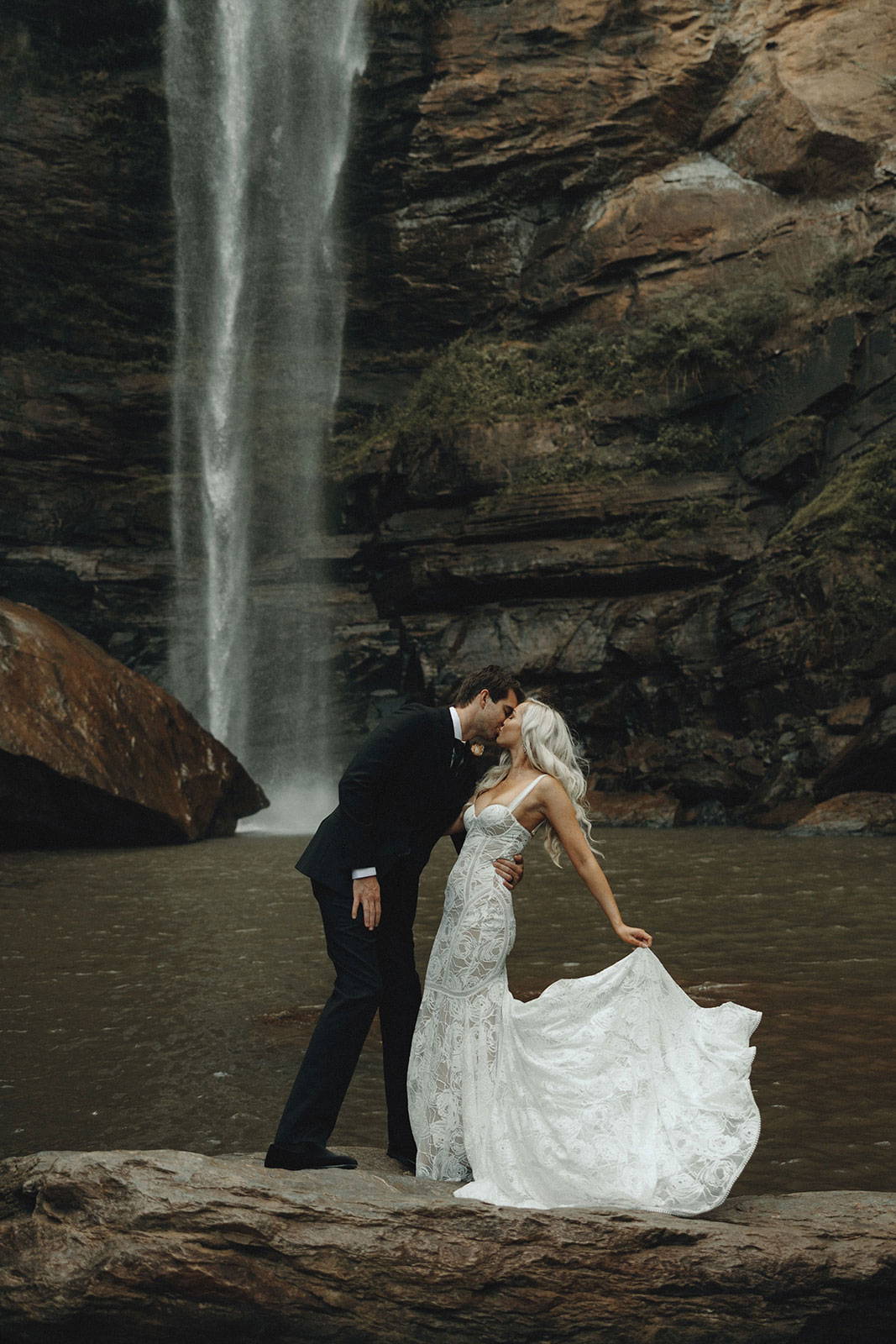 Bride and Groom sharing a kiss with waterfall background