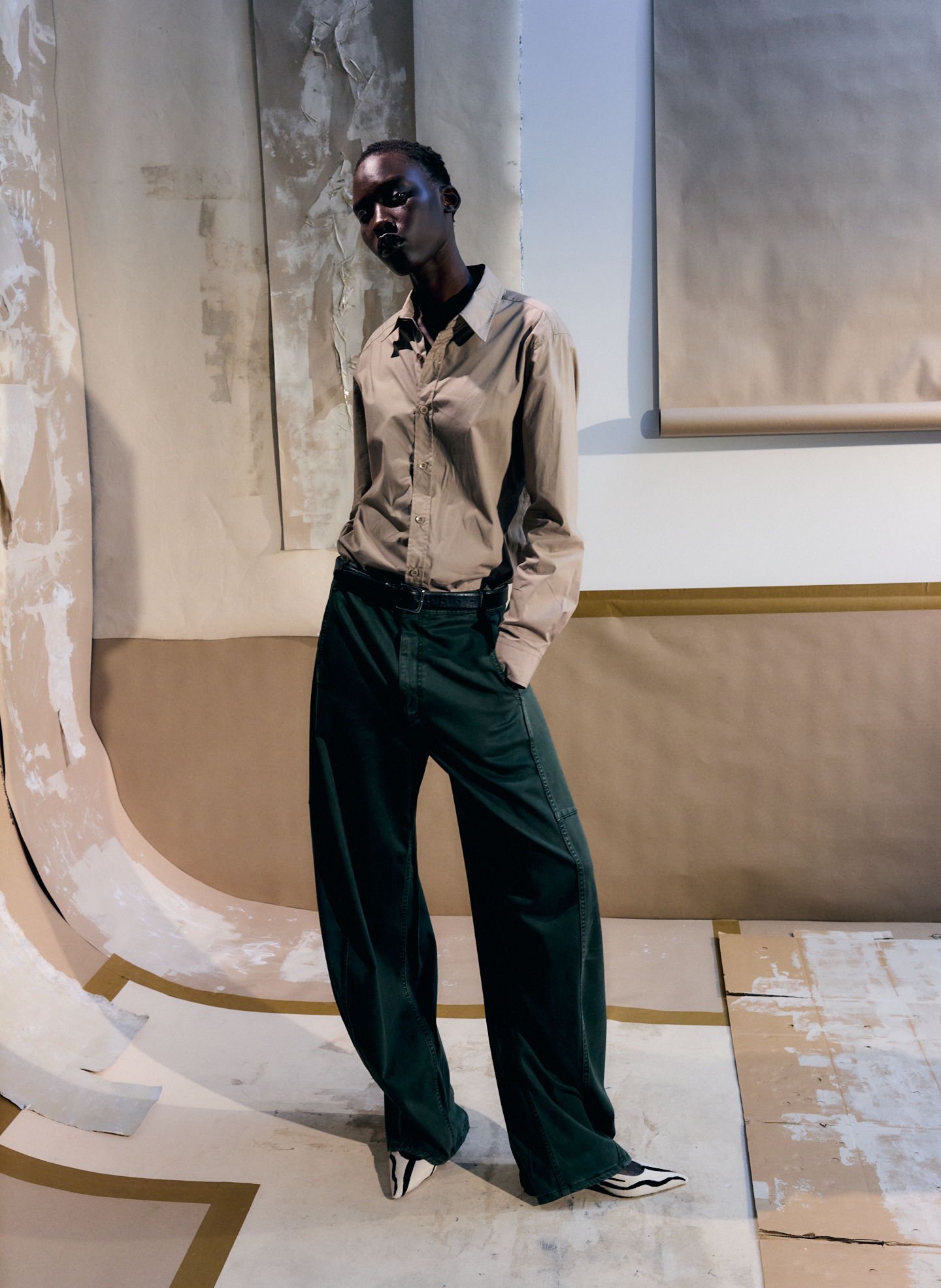 Model in a stylish outfit poses against an artistic backdrop.