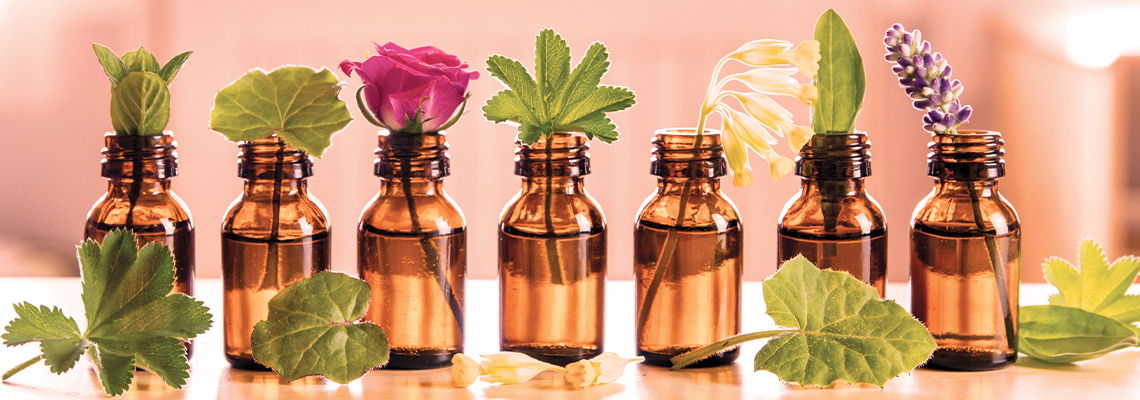 Brown bottles with various herbs and flowers on top.